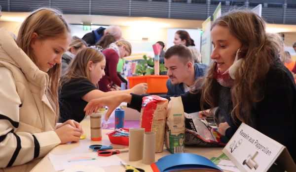 Kinder basteln Rasseln aus Papprollen.