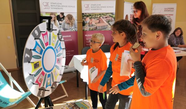 Kinder drehen an einem Glücksrad.