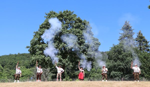 Mitglieder des Schützenvereins stehen auf einer Wiese und schießen in die Luft.