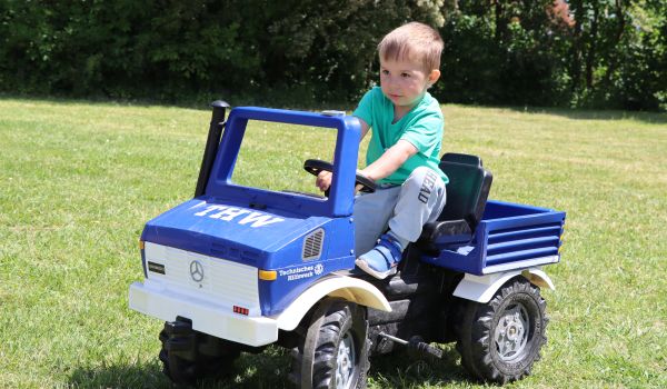 Ein Kind sitzt auf einem kleinen TWH-Auto.
