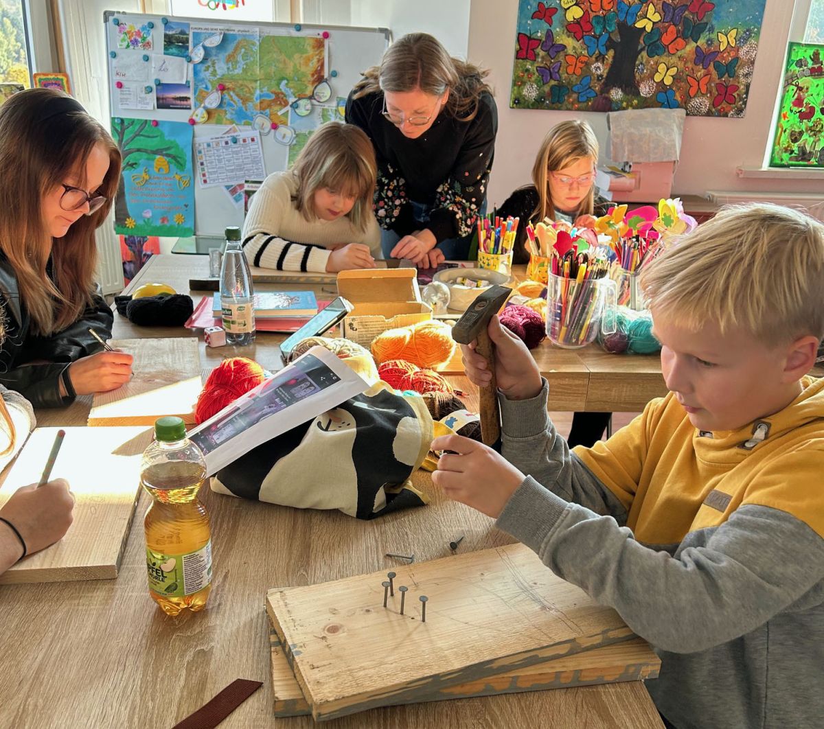 Jungs und Mädchen basteln Nagelbretter.