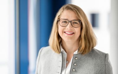 Eine Frau steht vor einem Fenster. Es ist die Pressesprecherin Cindy Heinkel.