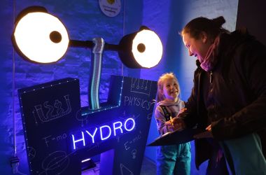 Auf einer H-förmigen Schild leuchtet das Wort ''Hydro'' blau.