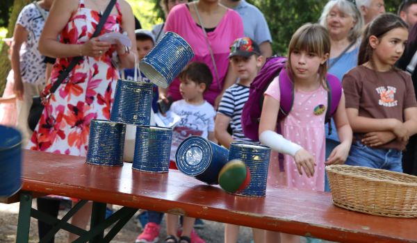 Kinder stehen vor einem Stand mit Dosenwerfen.