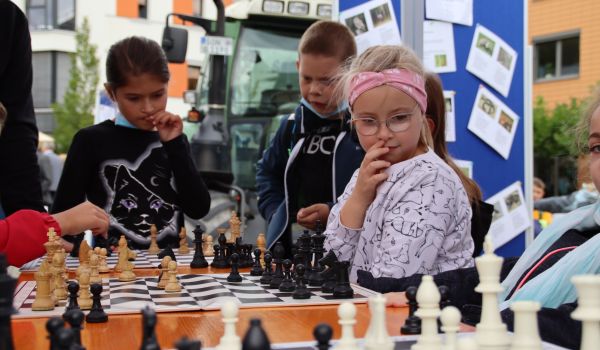 Kinder sitzen an einem Tisch und spielen Schach.