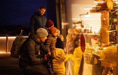 Eine Familie schaut am Spielzeugmuseum in eine weihnachtlich dekorierte Kulisse.