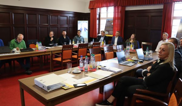 Mehrere Personen sitzen an einem u-förmigen Tisch.