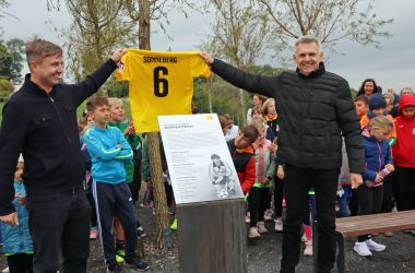 Zwei Männer halten ein gelbes Fußballtrikot mit der Nummer 6 und dem Schriftzug Sonneberg in die Höhe.