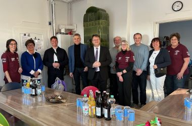 Zehn Frauen und Männer stehen während der Eröffnung eines neuen Gemeinschaftsraumes in einer Reihe.