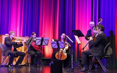 Fünf Personen machen Musik auf einer Bühne.