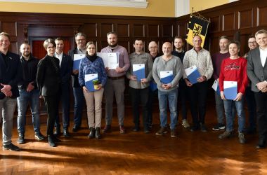 Eine Gruppe von Menschen hält ein Zertifikat in den Händen.