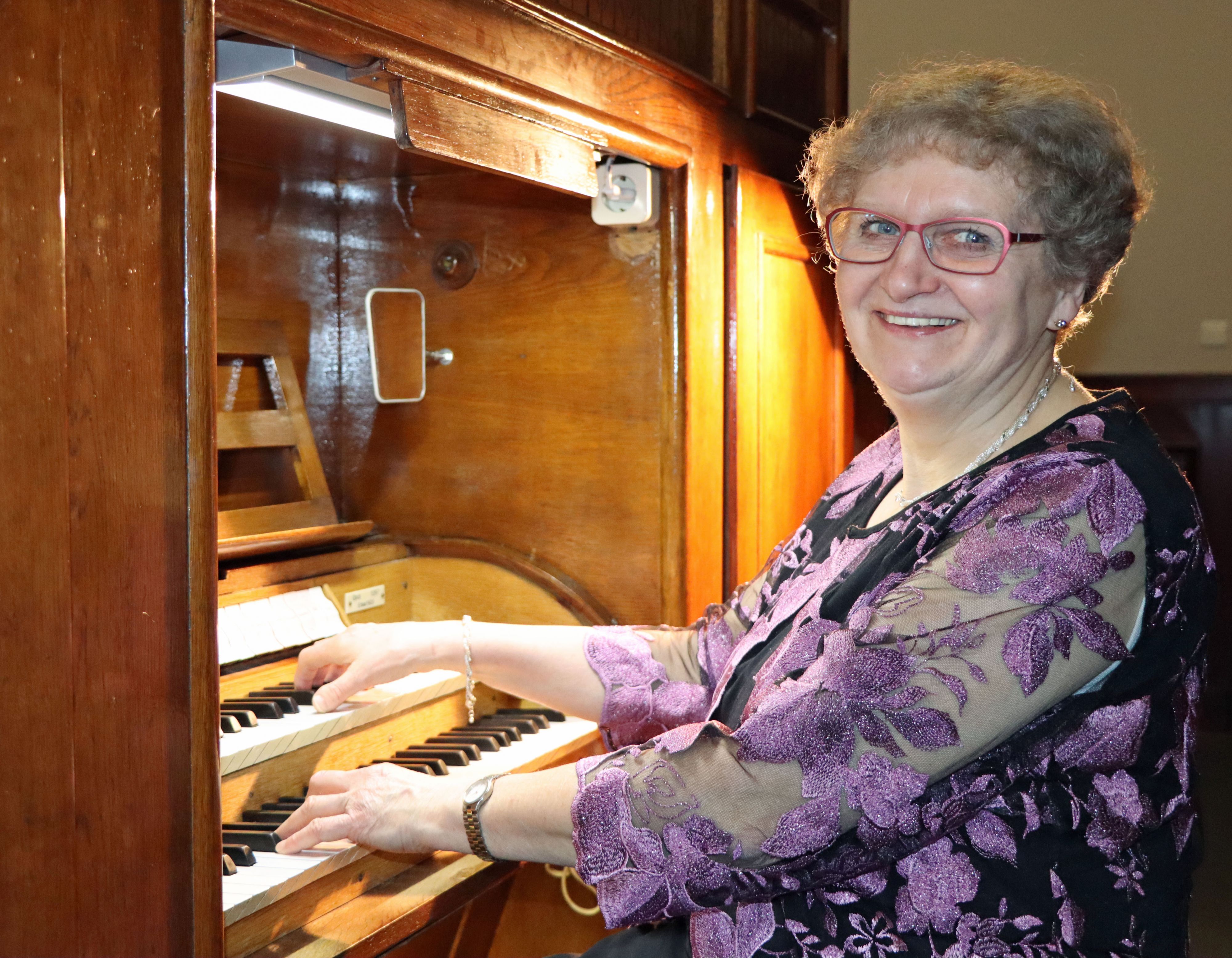 Eine Frau sitzt vor einer Orgel und spielt darauf.