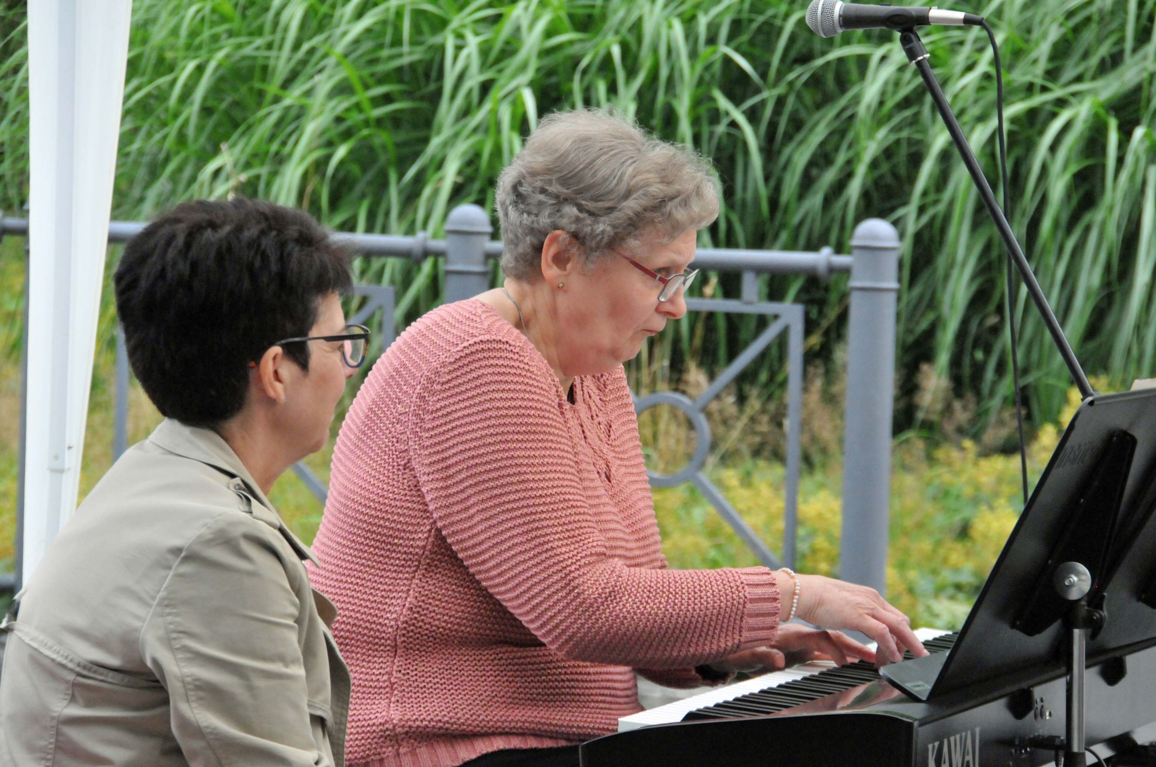 Eine Frau sitzt an einem Keyboard und spielt. Eine andere Frau sitzt daneben.