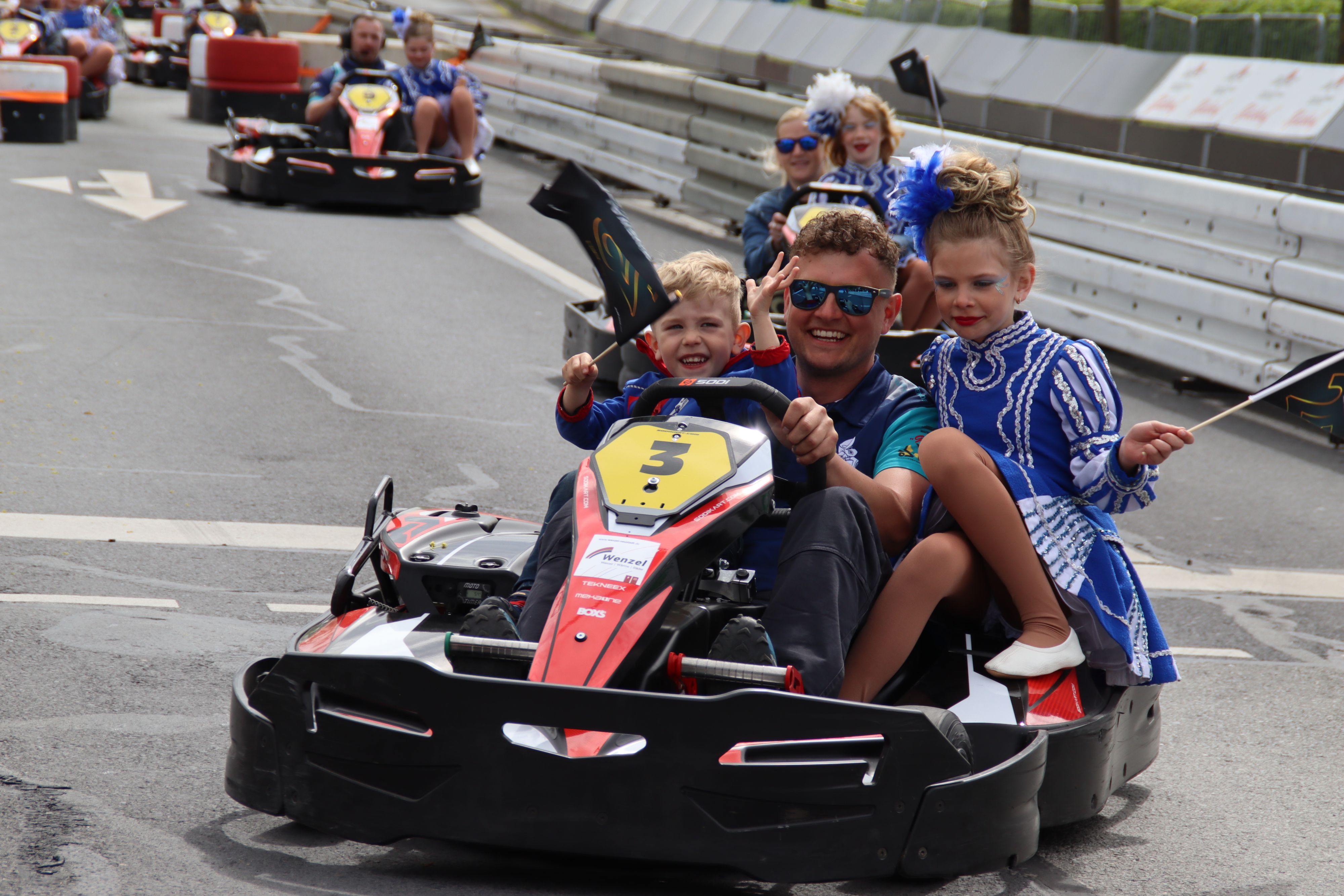 Menschen fahren in Kartautos über eine Rennstrecke.