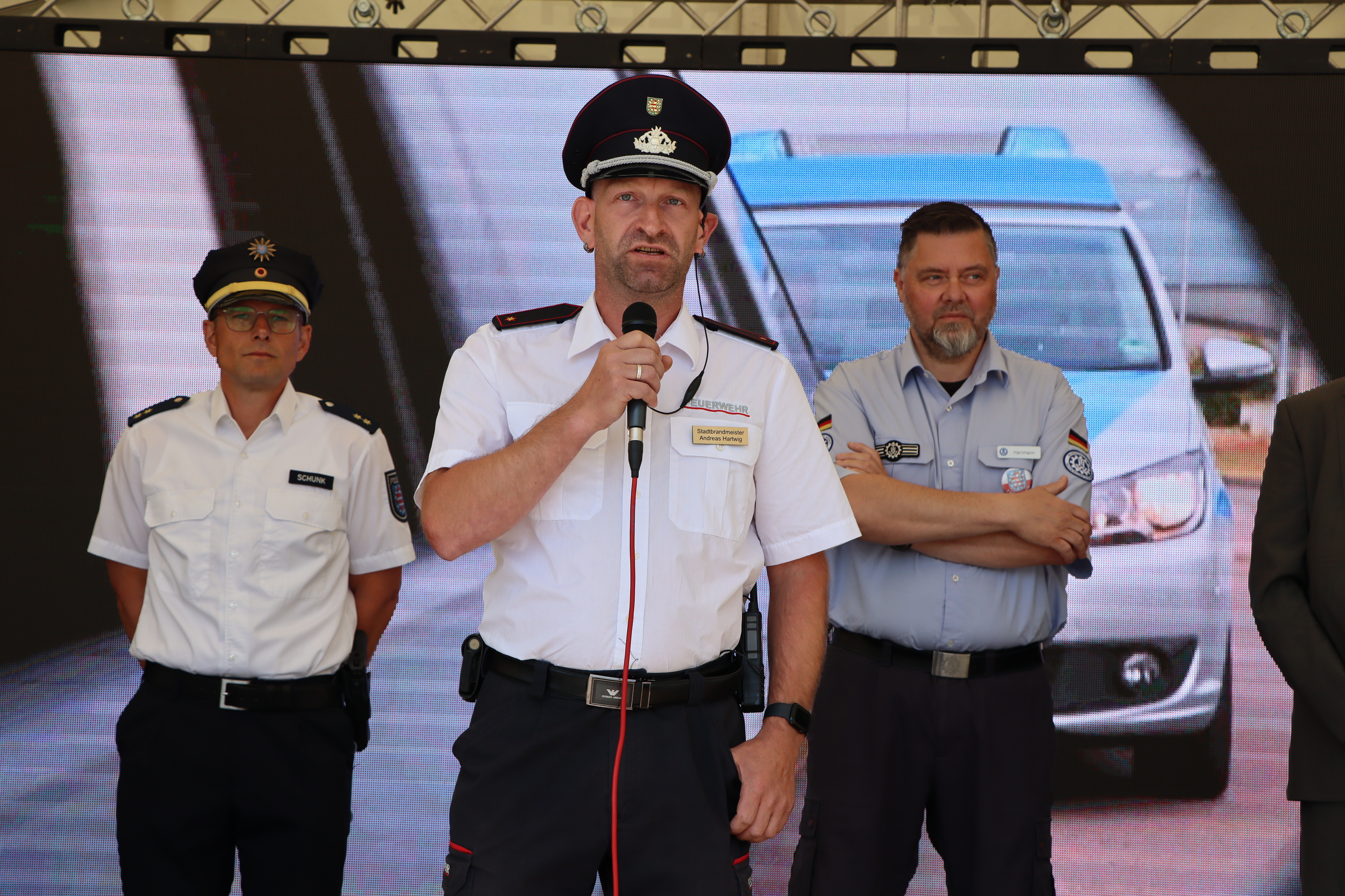Männer in Uniform stehen auf einer Bühne und begrüßen die Gäste.