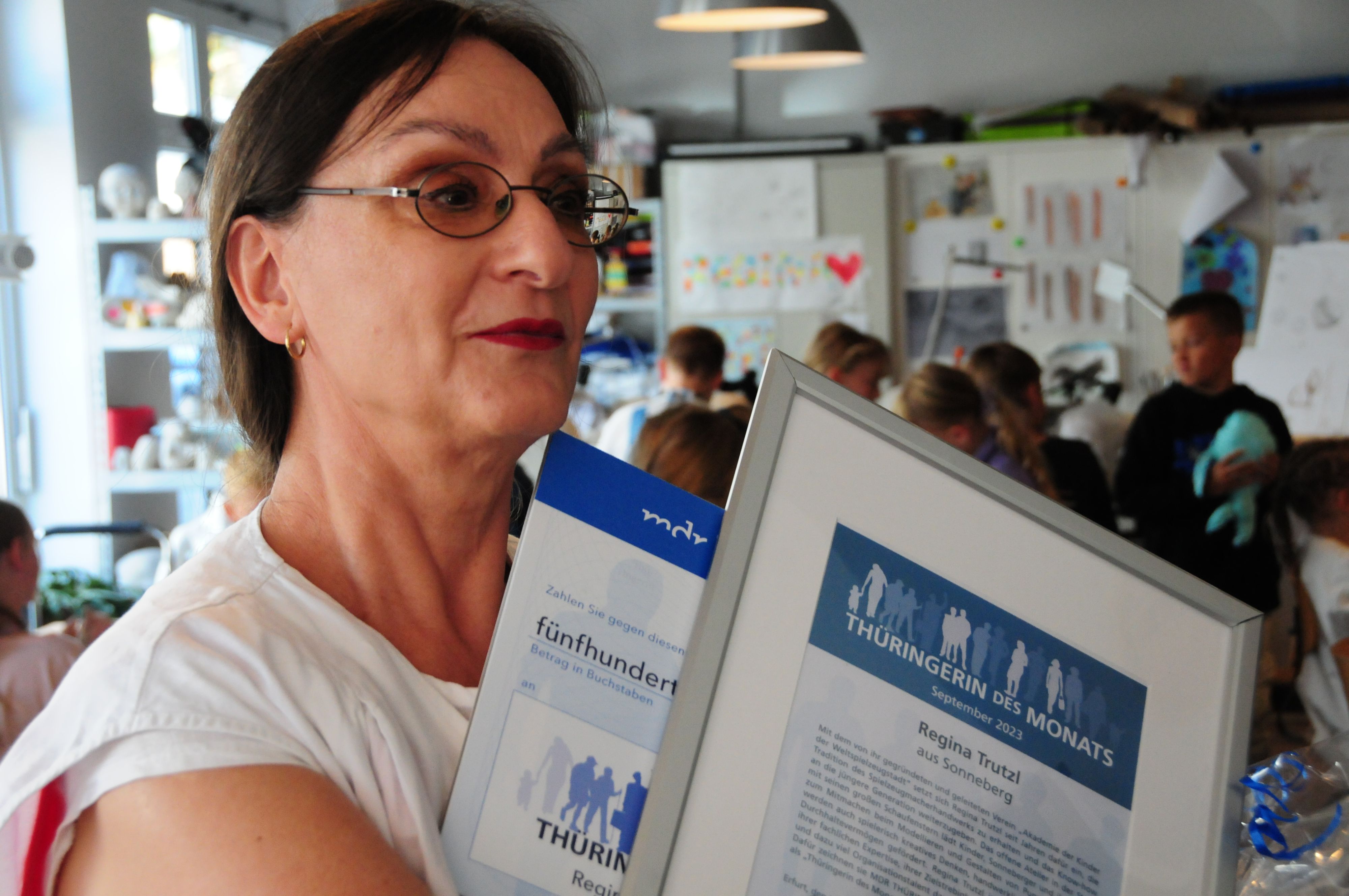 Eine Frau hält einen Auszeichnung mit der Aufschrift: Thüringerin des Monats.
