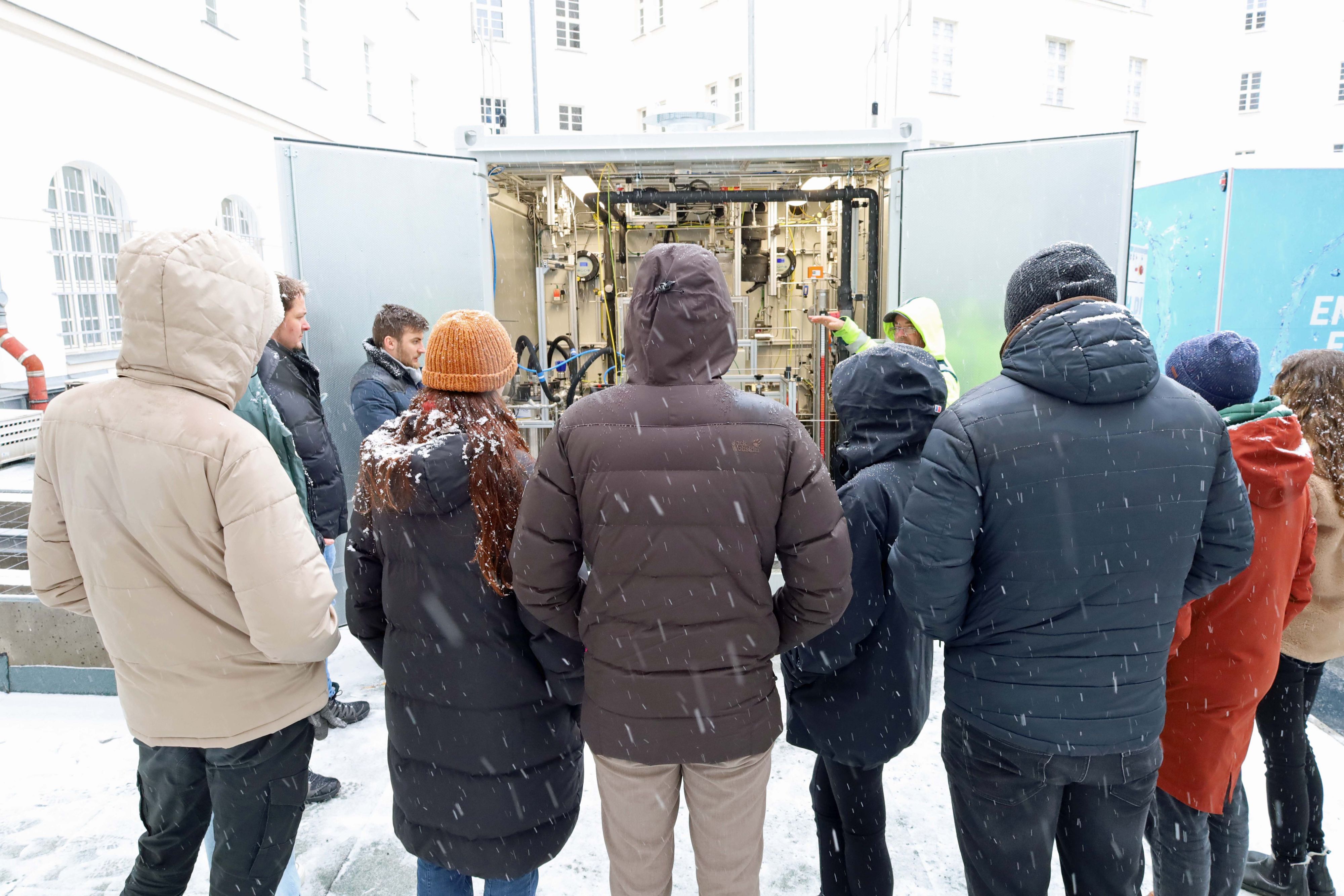 Interessierte Gäste schauen sich eine technische Anlage in einem Container an.