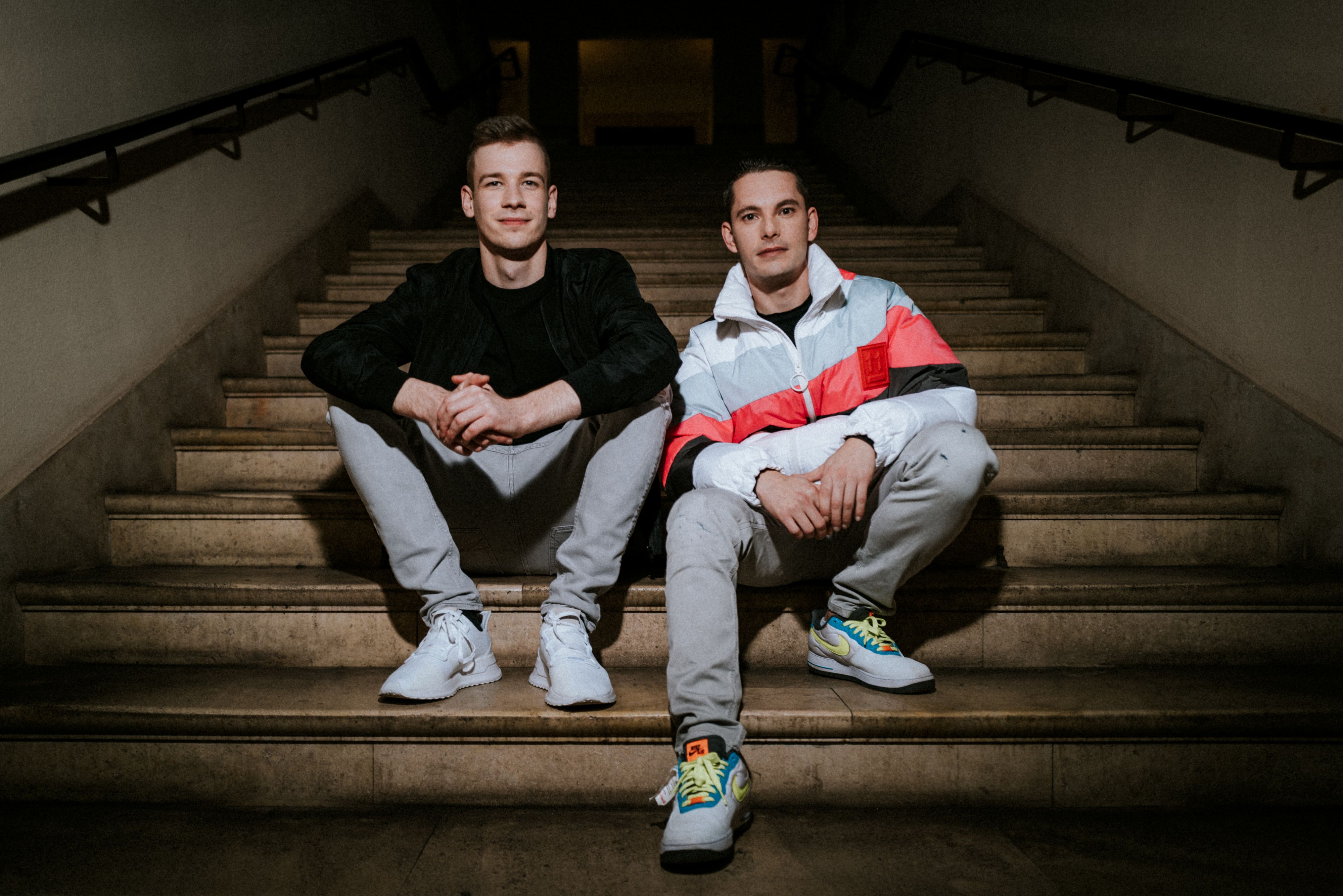 Zwei junge Männer sitzen auf einer Treppe.