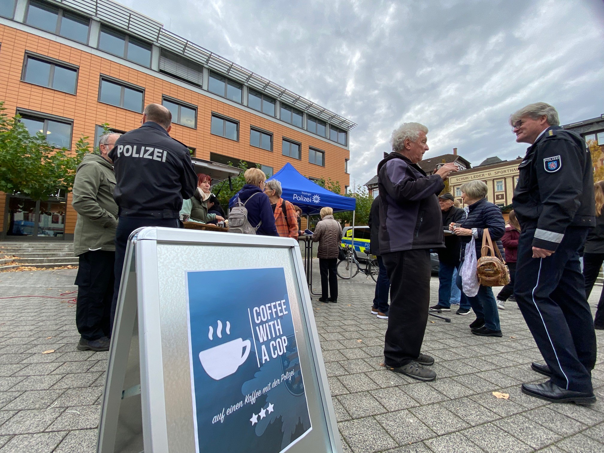 Polizisten und Passanten stehen ins Gespräch vertieft auf einem Marktplatz.