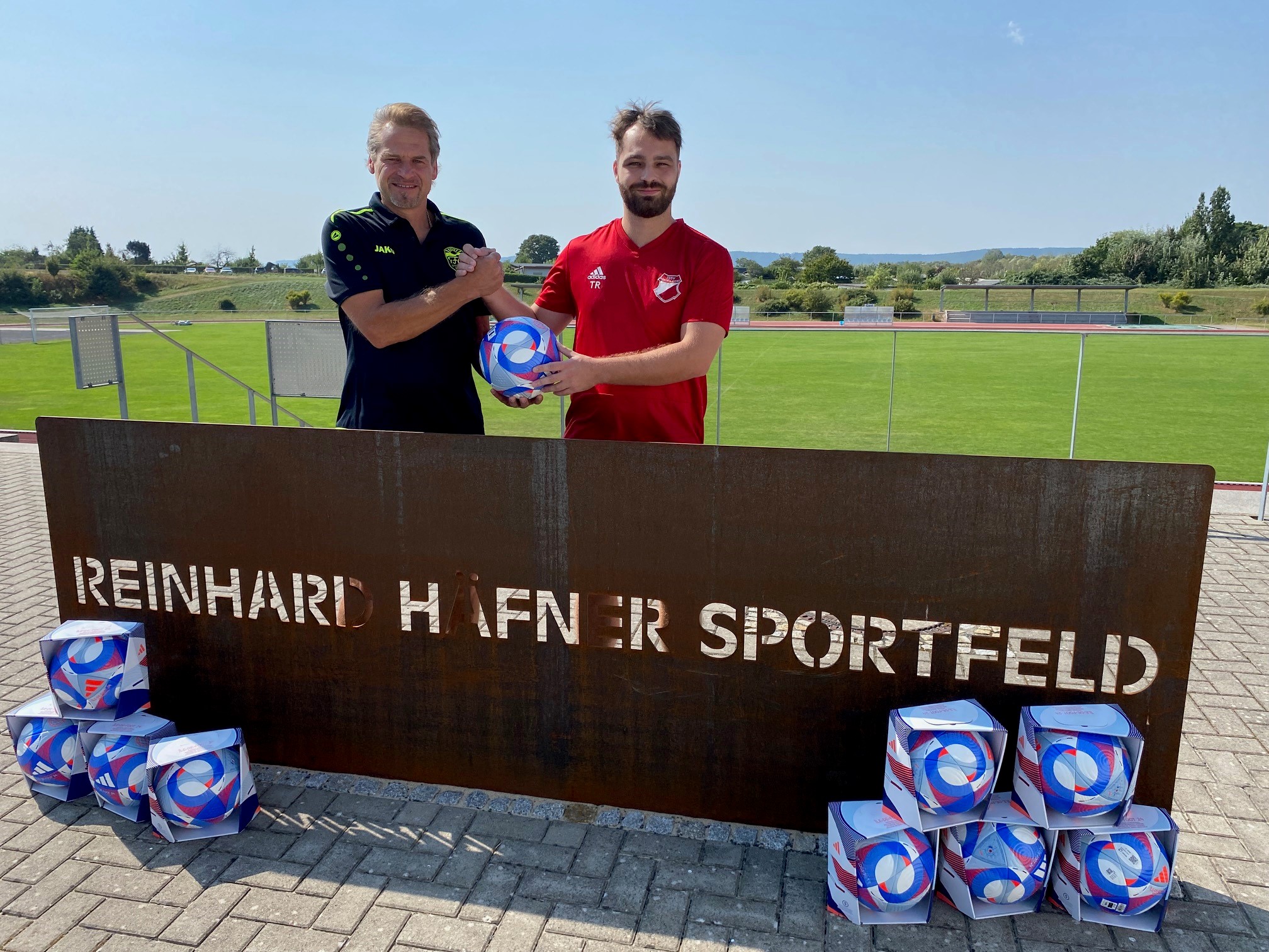 Zwei Männer halten einen Fußball.