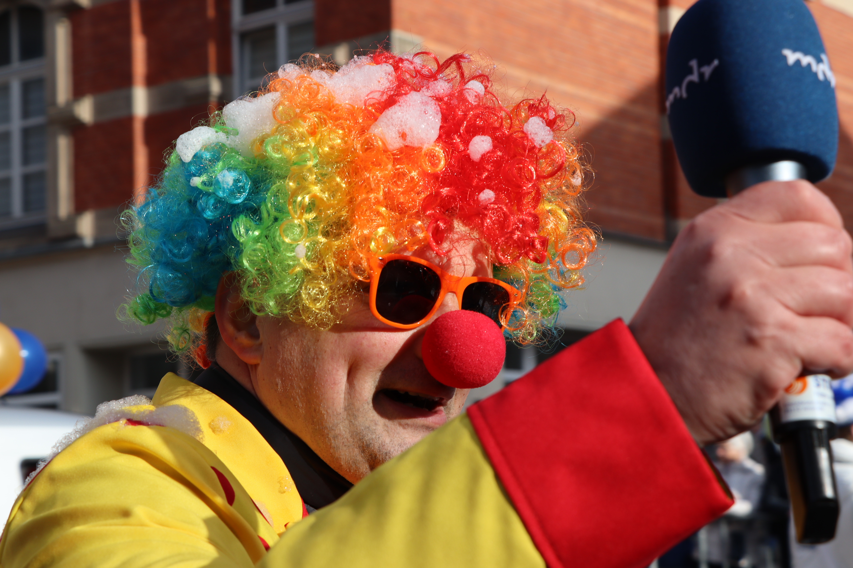 Ein Mann ist als Clown verkleidet. Er hält ein Mikrofon mit der Aufschrift: mdr.