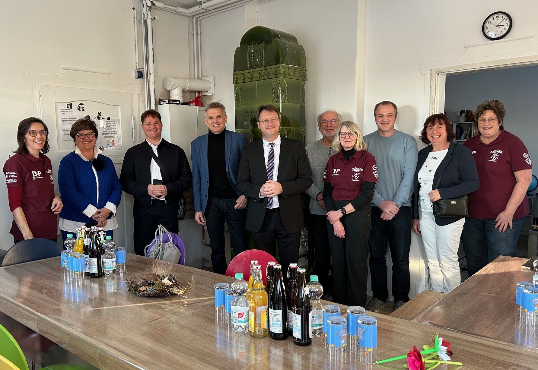 Zehn Frauen und Männer stehen während der Eröffnung eines neuen Gemeinschaftsraumes in einer Reihe.